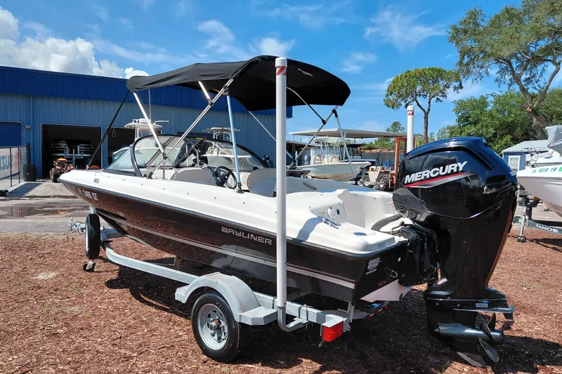 Slide: The Image of 2021 Bayliner 160 Bowrider boat with Mercury engine on trailer, parked outdoors. - 5
