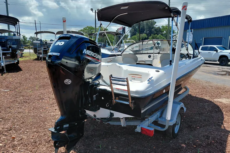 Slide: The Image of 2021 Bayliner 160 Bowrider with Mercury engine on trailer, parked outdoors. - 7