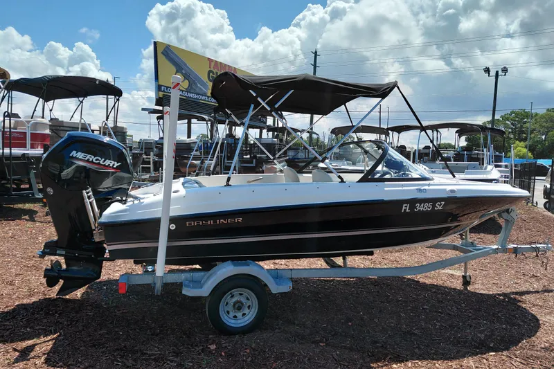 Slide: The Image of 2021 Bayliner 160 Bowrider boat on trailer, with Mercury outboard motor, under sunny skies. - 8