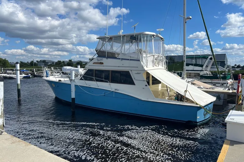 The Image of 1985 Hatteras 52 Convertible yacht docked at marina, featuring blue hull and spacious deck. - 0