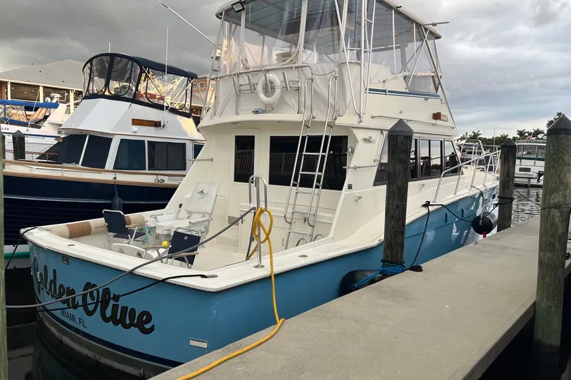 The Image of 1985 Hatteras 52 Convertible yacht docked at marina, featuring blue hull and spacious deck. - 1