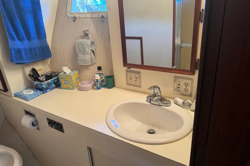 Slide: The Image of Bathroom sink area on a 1985 Hatteras 52 Convertible yacht, featuring toiletries and a mirror. - 11