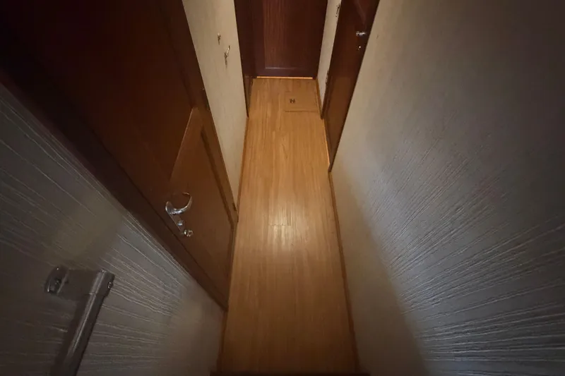 Slide: The Image of Narrow hallway inside 1985 Hatteras 52 Convertible yacht with wooden flooring and doors. - 18