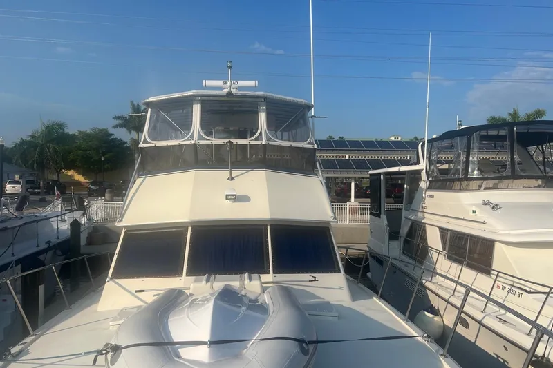 Slide: The Image of 1985 Hatteras 52 Convertible yacht docked at marina under clear blue sky. - 2
