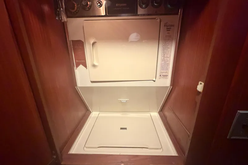 Slide: The Image of Laundry area inside 1985 Hatteras 52 Convertible yacht with dryer and wooden cabinetry. - 35