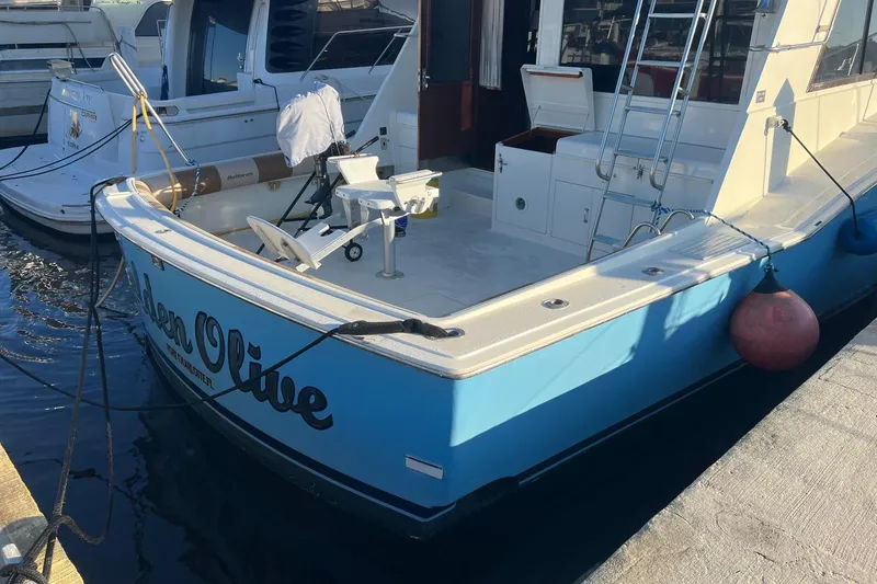 Slide: The Image of 1985 Hatteras 52 Convertible yacht docked, featuring a spacious deck and fishing chair. - 4