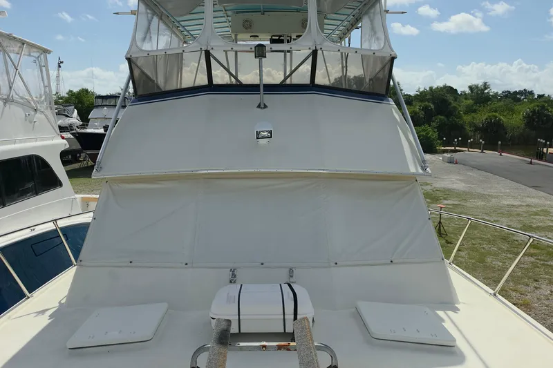 Slide: The Image of 1985 Hatteras 52 Convertible yacht with covered flybridge, docked under a clear sky. - 40