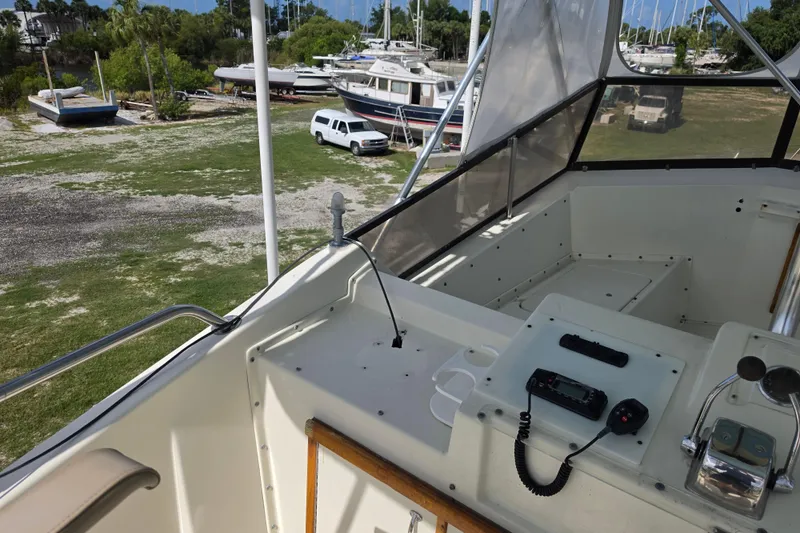 Slide: The Image of 1985 Hatteras 52 Convertible yacht cockpit with control panel, overlooking marina and parked vehicles. - 46
