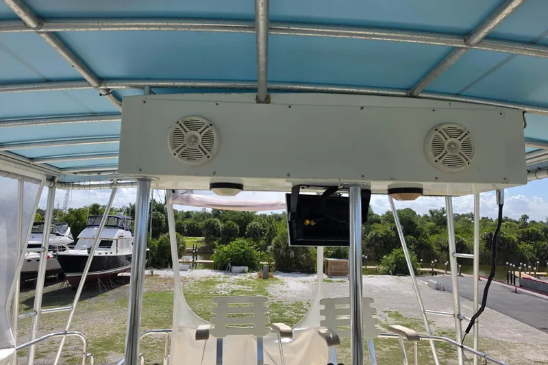Slide: The Image of 1985 Hatteras 52 Convertible boat deck with speakers and canopy, docked near other boats. - 52