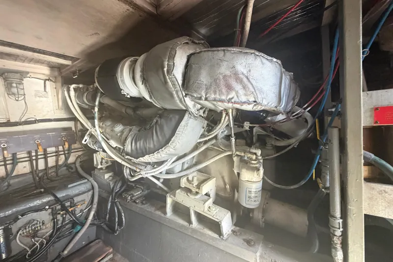 Slide: The Image of Engine room of a 1985 Hatteras 52 Convertible yacht, showing complex machinery and wiring. - 76