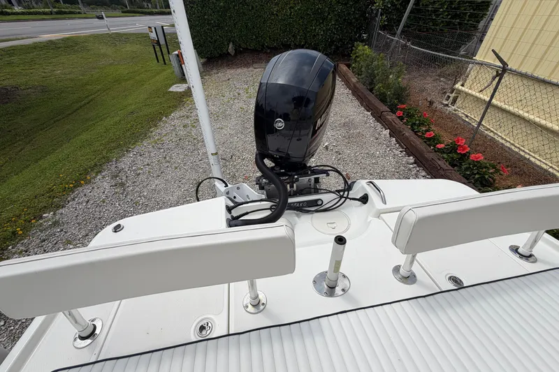 Slide: The Image of 2017 Mako 21 LTS boat with outboard motor, parked on gravel near flowers. - 13