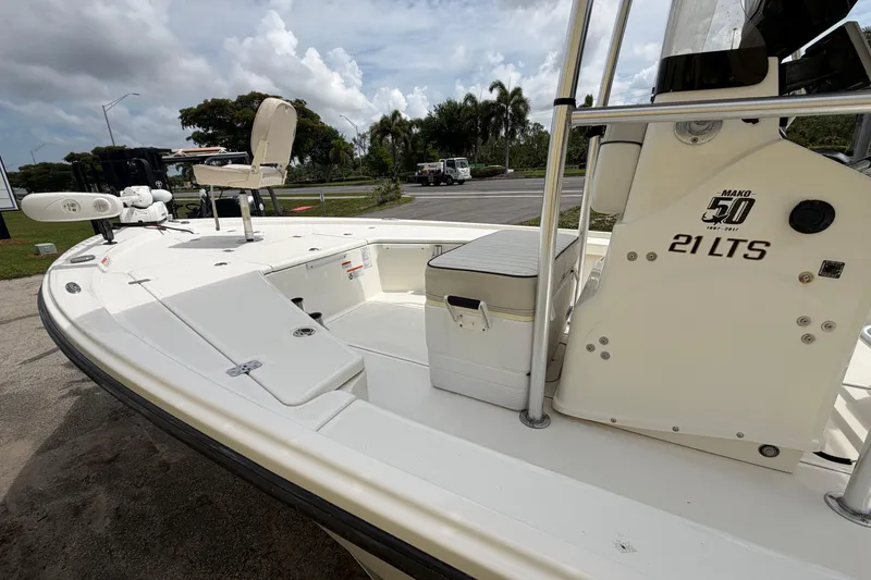 Slide: The Image of 2017 Mako 21 LTS boat with seating and storage, parked outdoors under cloudy skies. - 5