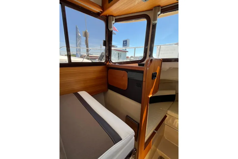 Slide: The Image of Interior view of 2017 Ranger Tugs R-27 boat, showcasing wood paneling and seating. - 19