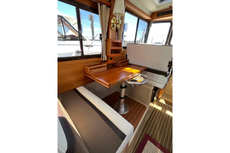 Slide: The Image of Interior of 2017 Ranger Tugs R-27 with wooden table and seating area. - 20