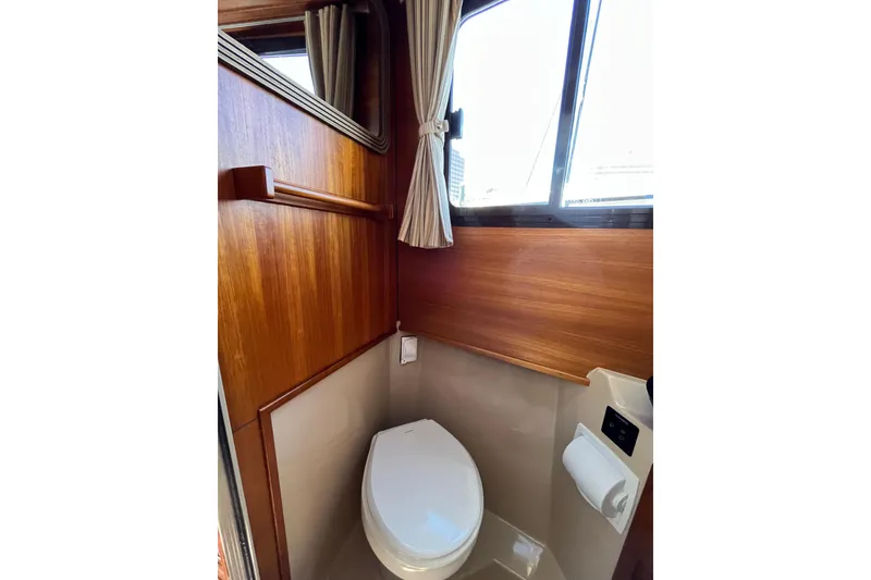 Slide: The Image of 2017 Ranger Tugs R-27 boat bathroom with wooden paneling and window. - 22