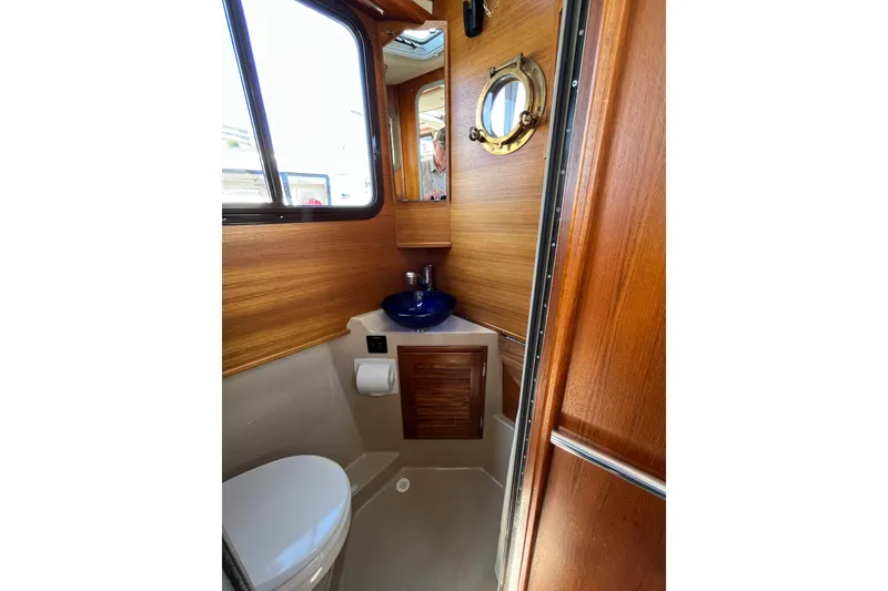Slide: The Image of 2017 Ranger Tugs R-27 boat bathroom with wooden interior and blue sink. - 24