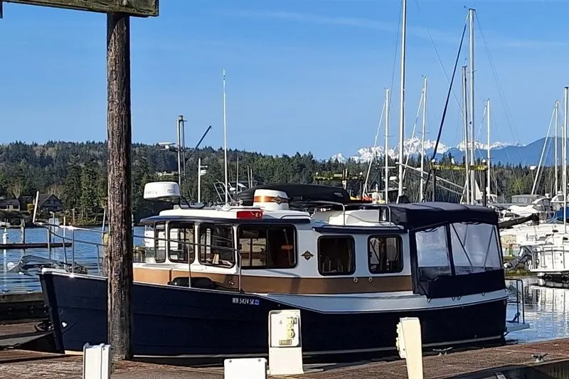 Slide: The Image of 2017 Ranger Tugs R-27 docked at a marina with scenic mountain backdrop. - 3