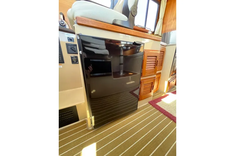 Slide: The Image of 2017 Ranger Tugs R-27 interior with compact fridge and wooden cabinetry. - 32