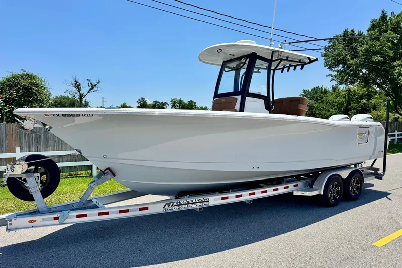 The Image of 2024 Sea Hunt Gamefish 27 Coffin Box boat on trailer, parked on a sunny street. - 1