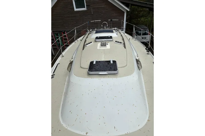 Slide: The Image of 1987 Ericson 28/2 sailboat deck view, showing hatches and rigging near a wooden building. - 18
