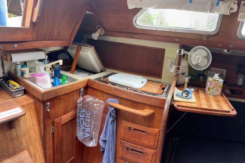 Slide: The Image of 1987 Ericson 28/2 sailboat galley with wooden cabinetry, sink, and countertop essentials. - 41