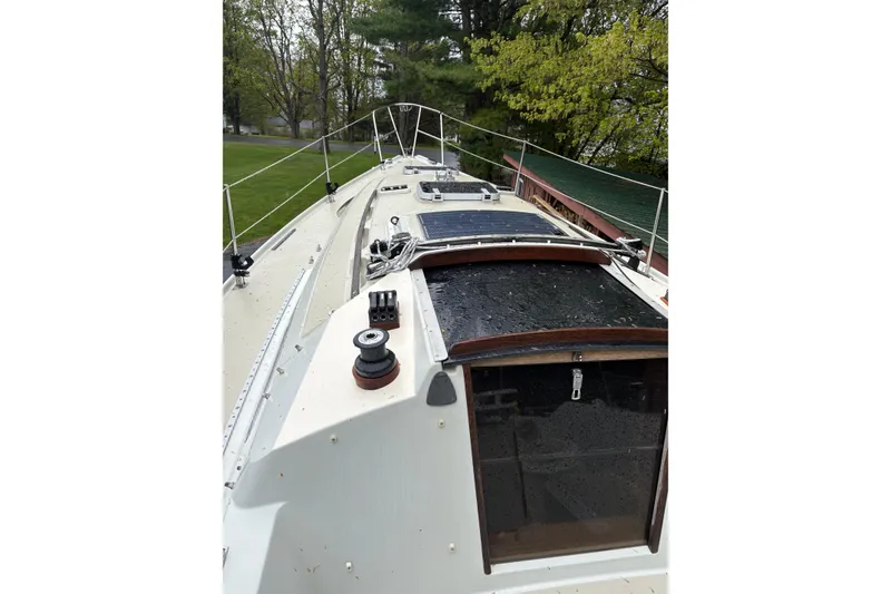 Slide: The Image of 1987 Ericson 28/2 sailboat deck with winches and hatch, surrounded by greenery. - 8