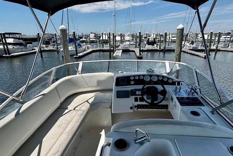 Slide: The Image of 2001 Silverton 330 Sport Bridge yacht interior at marina, showcasing helm and seating area. - 5