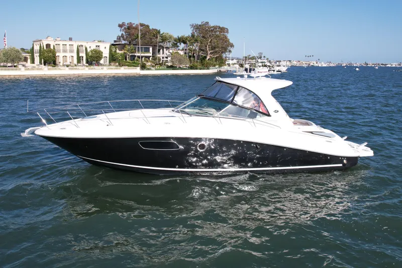 The Image of 2009 Sea Ray Sundancer 350 yacht cruising on a sunny day near waterfront homes. - 0