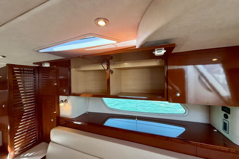 Slide: The Image of Interior of 2009 Sea Ray Sundancer 350 yacht with open wooden cabinets and window view. - 15