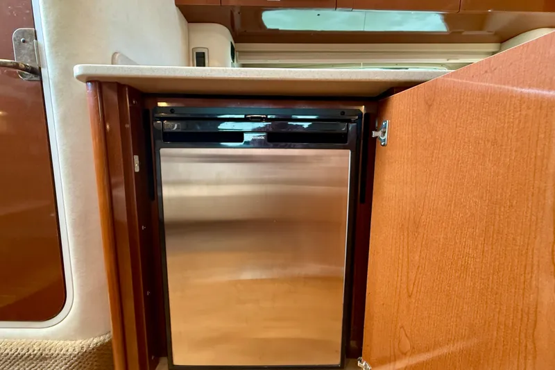 Slide: The Image of 2009 Sea Ray Sundancer 350 interior with stainless steel mini fridge in wooden cabinet. - 31
