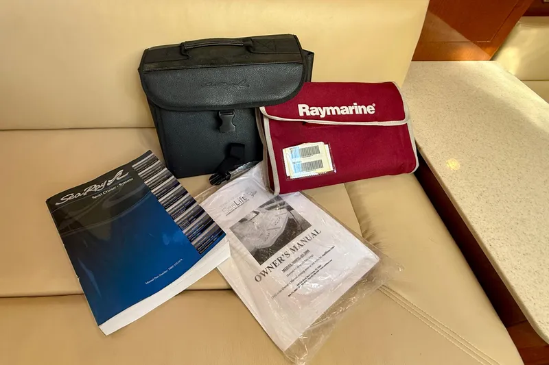 Slide: The Image of Owner's manuals and accessories for 2009 Sea Ray Sundancer 350 on a beige seat. - 60