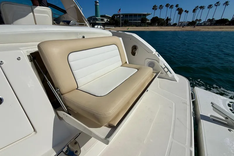 Slide: The Image of 2009 Sea Ray Sundancer 350 boat with beige and white seating, docked near a scenic shoreline. - 76