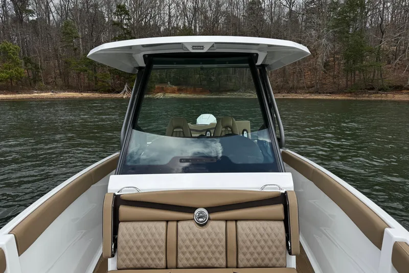 Slide: The Image of 2026 Monterey Elite 25 OB boat on a calm lake with wooded shoreline. - 11