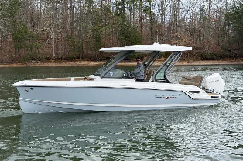 Slide: The Image of 2026 Monterey Elite 25 OB boat cruising on a calm lake with wooded shoreline. - 6