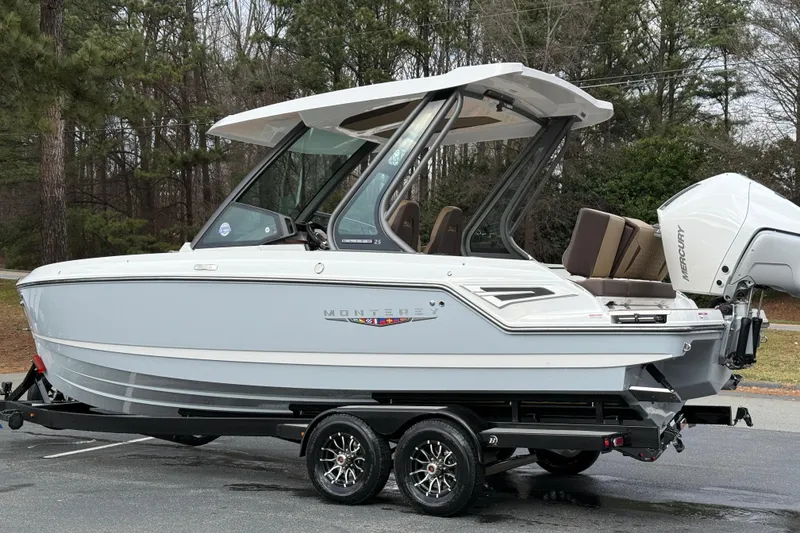 Slide: The Image of 2026 Monterey Elite 25 OB boat on trailer, parked outdoors, featuring sleek design and modern outboard motor. - 7
