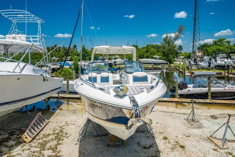 Slide: The Image of 2013 Chaparral 327 SSX boat on dry dock, surrounded by other boats, under a clear blue sky. - 79