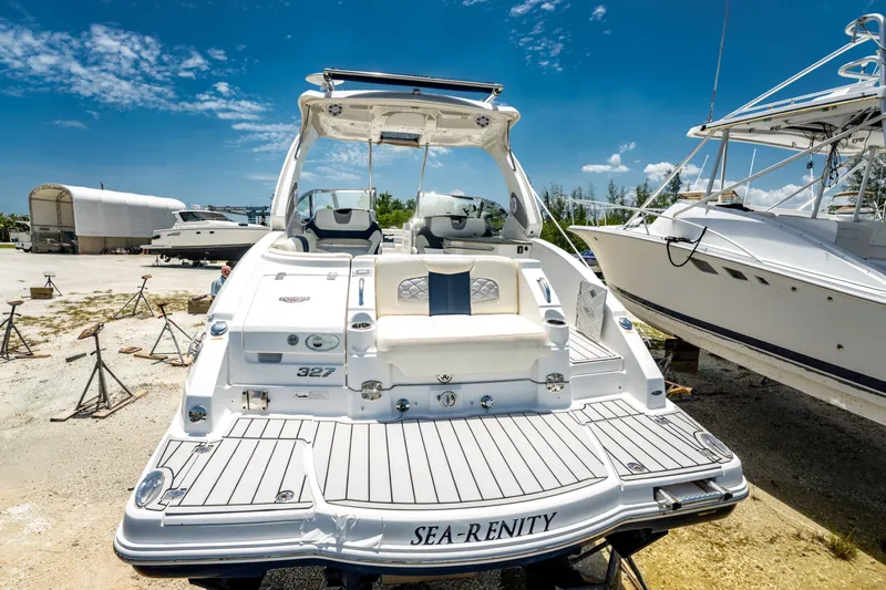 Slide: The Image of 2013 Chaparral 327 SSX boat docked, featuring spacious deck and seating under clear blue sky. - 77