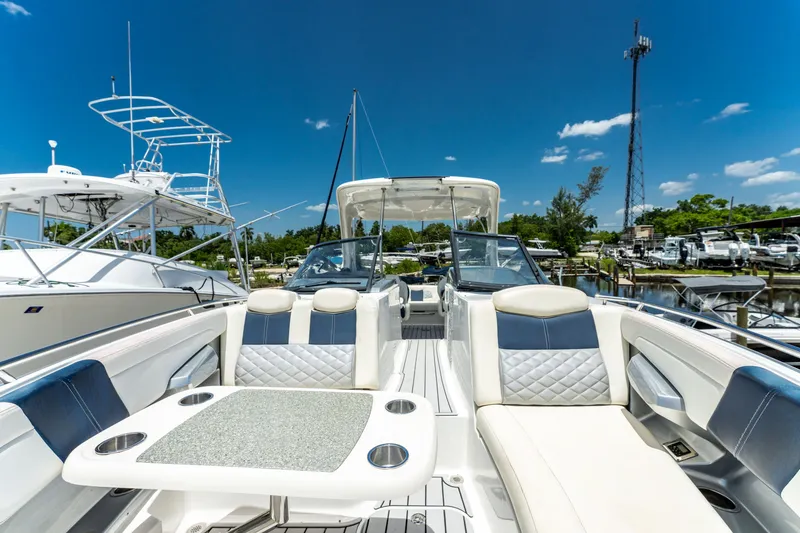Slide: The Image of 2013 Chaparral 327 SSX boat interior with seating and table, docked under clear blue sky. - 63