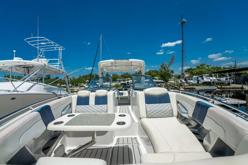 Slide: The Image of 2013 Chaparral 327 SSX boat interior with luxurious seating and table, docked under clear blue sky. - 61