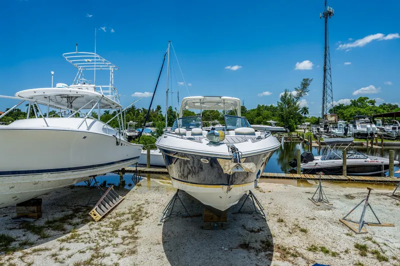 Slide: The Image of 2013 Chaparral 327 SSX boat on dry dock, surrounded by other vessels, under a clear blue sky. - 78