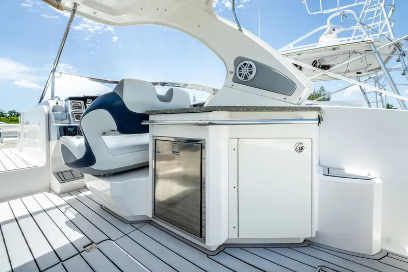 Slide: The Image of 2013 Chaparral 327 SSX boat interior with seating and kitchenette under a clear sky. - 67
