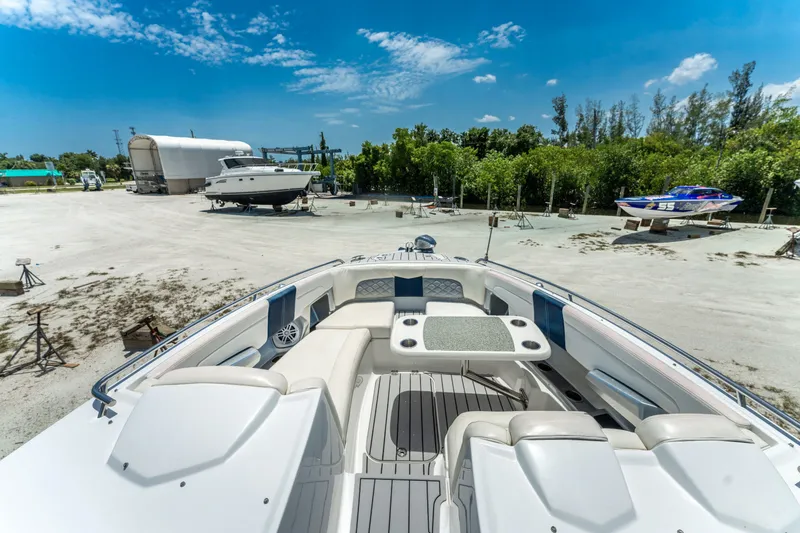 Slide: The Image of 2013 Chaparral 327 SSX boat interior with seating and table, parked outdoors under blue sky. - 58