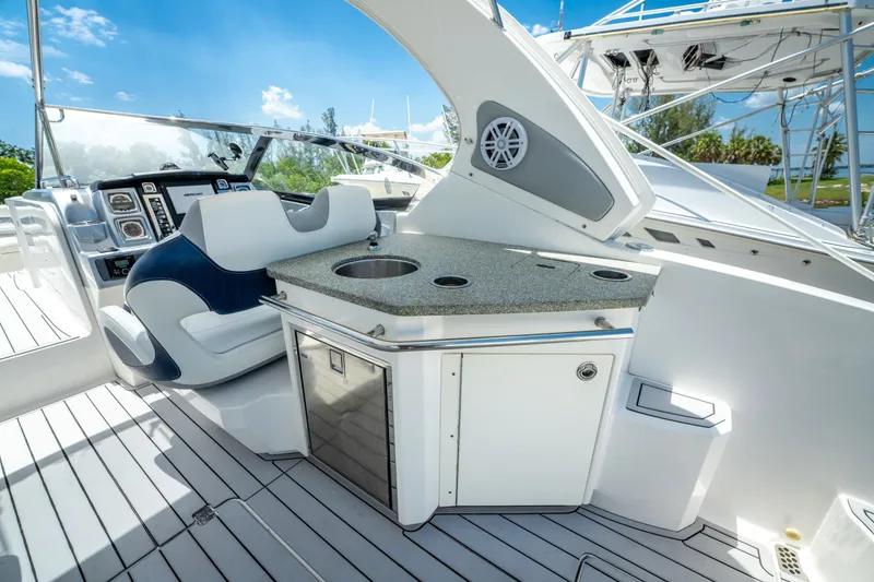 Slide: The Image of 2013 Chaparral 327 SSX boat interior with helm, seating, and kitchenette under clear blue sky. - 69