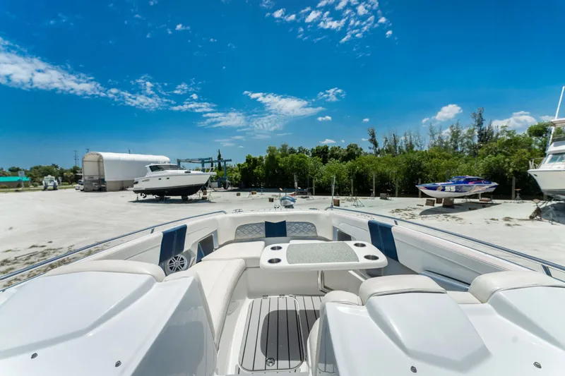 Slide: The Image of 2013 Chaparral 327 SSX boat interior with seating and table, parked outdoors under blue sky. - 57