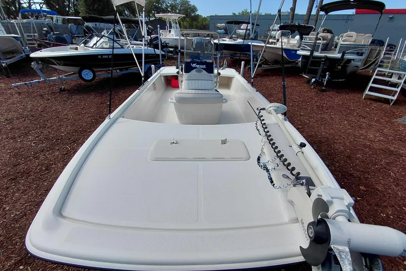 Slide: The Image of 2015 Mako Pro Skiff 17 CC boat in a marina, showcasing spacious deck and fishing equipment. - 13