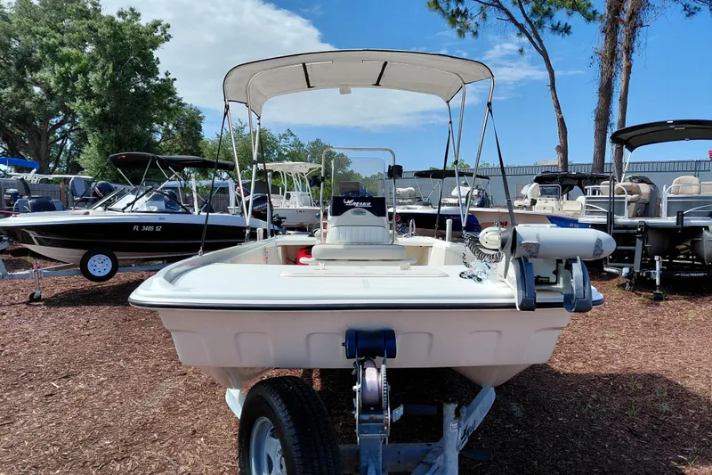 Slide: The Image of 2015 Mako Pro Skiff 17 CC boat on trailer, surrounded by trees and other boats. - 2