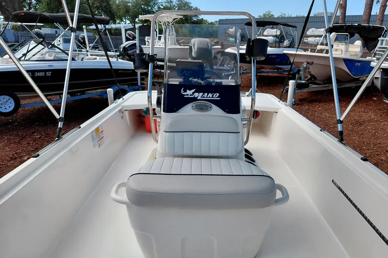 Slide: The Image of 2015 Mako Pro Skiff 17 CC boat interior with seating and console, parked among other boats. - 22