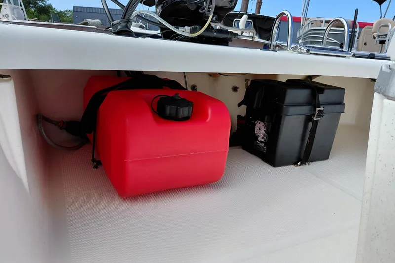 Slide: The Image of 2015 Mako Pro Skiff 17 CC storage area with red fuel tank and black battery box. - 32