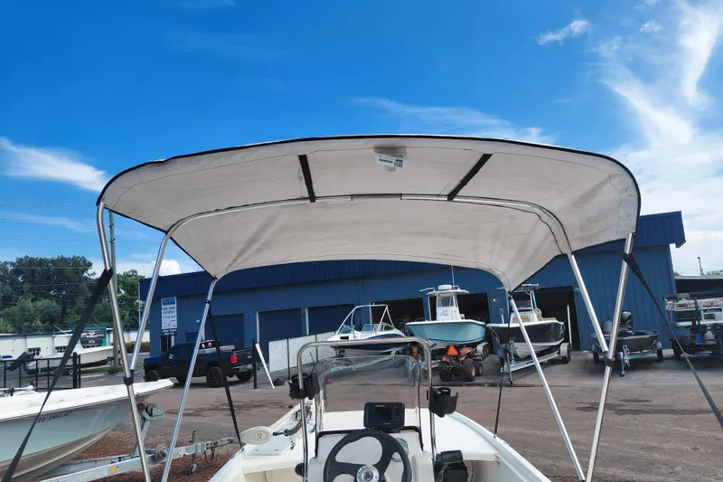 Slide: The Image of 2015 Mako Pro Skiff 17 CC with canopy, parked at a marina under a clear blue sky. - 37