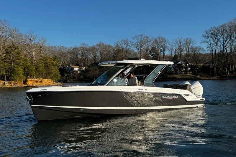 Slide: The Image of 2026 Monterey Elite 30 OB boat cruising on a serene lake with wooded shoreline. - 11
